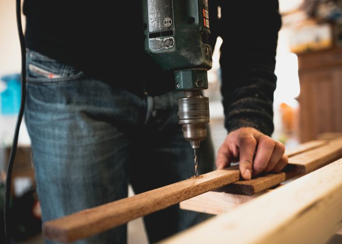 Man Holding Wooden Stick While Drilling Hole